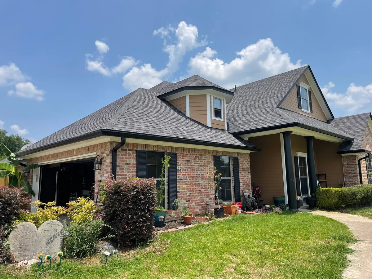 Brick home with a dormer and an attached garage, with dark gutters