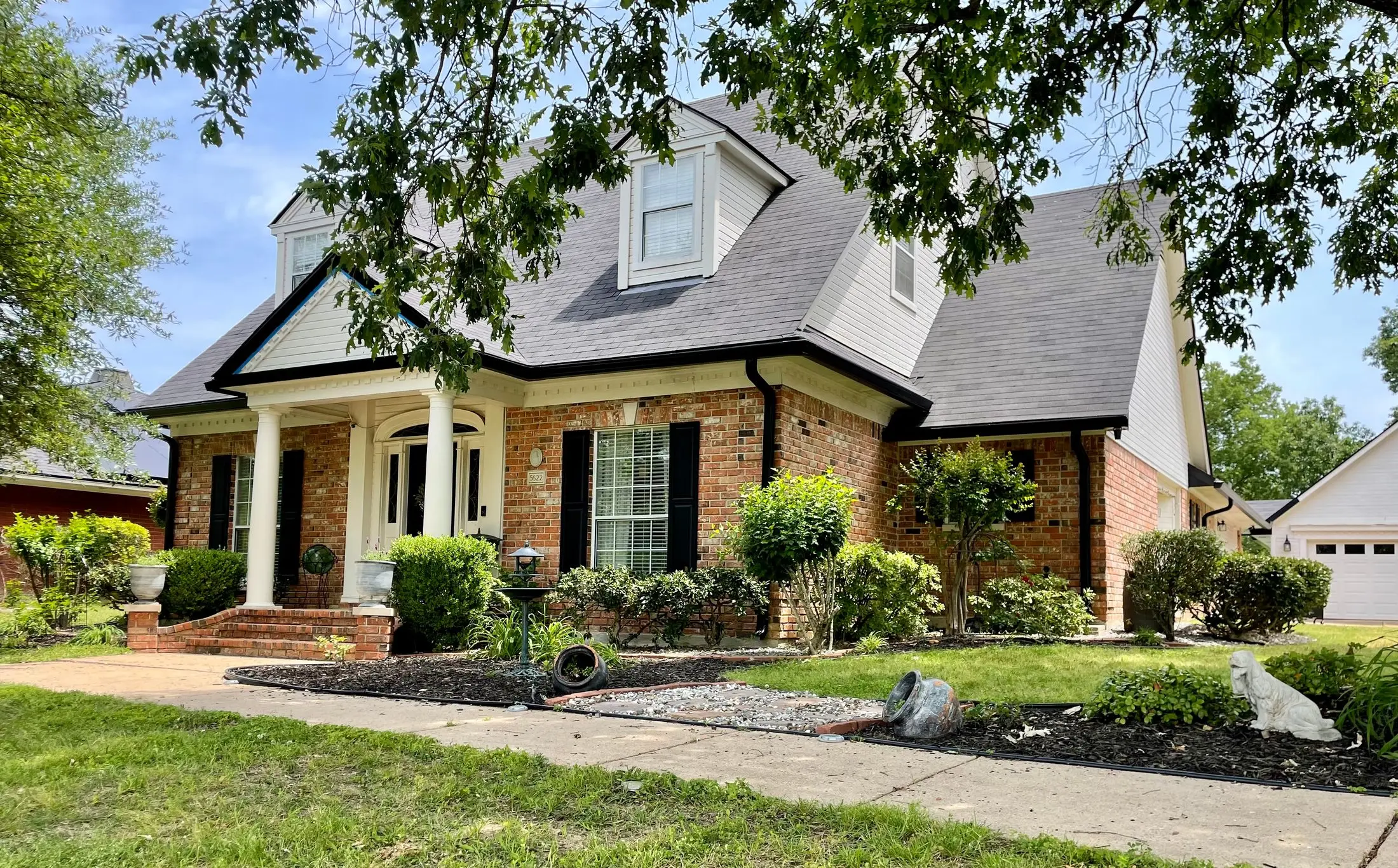Brick home with dormers, white columns and an arched entry