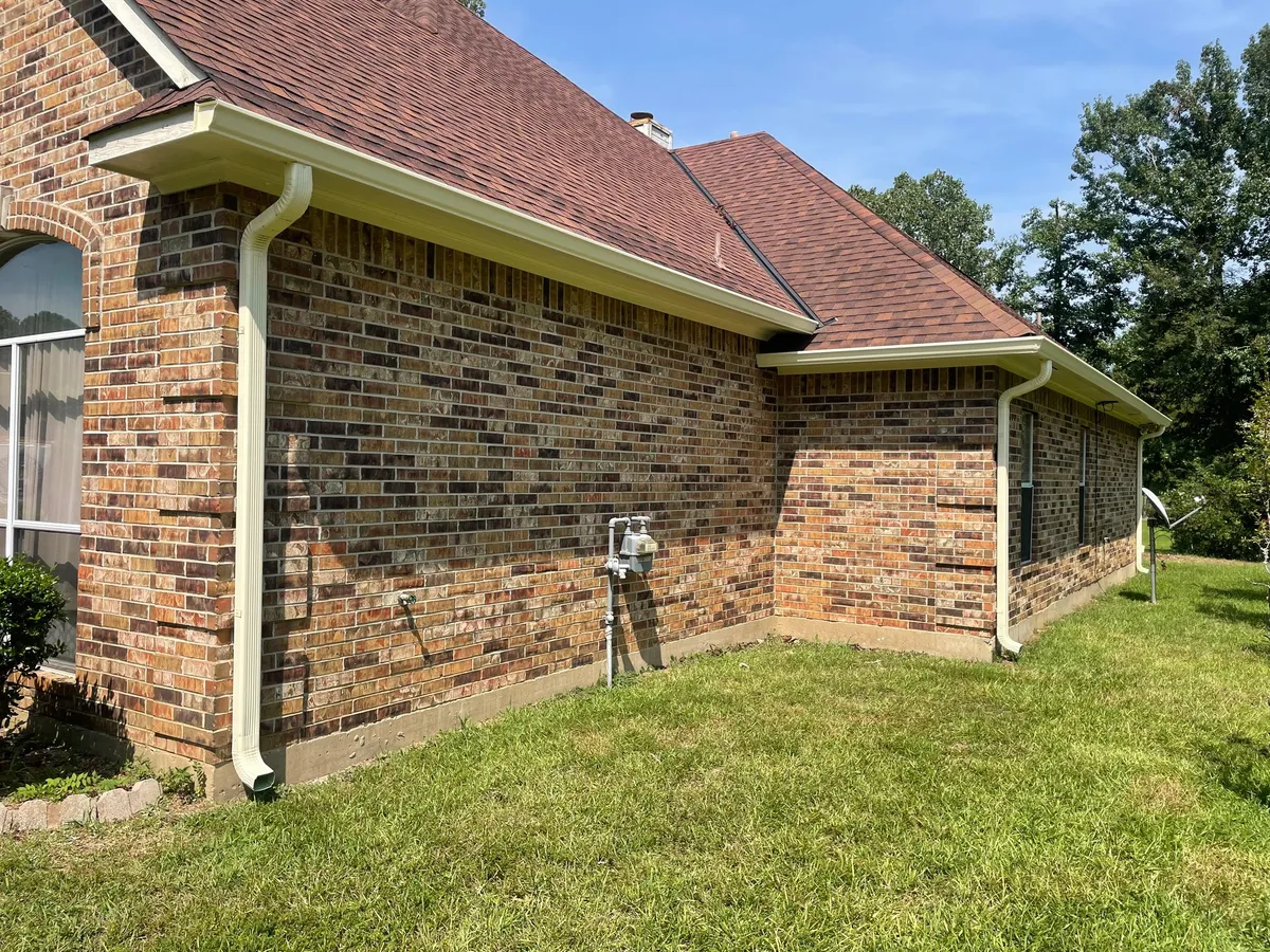 Brick side elevation with a white gutter run and a downspout carried to the ground