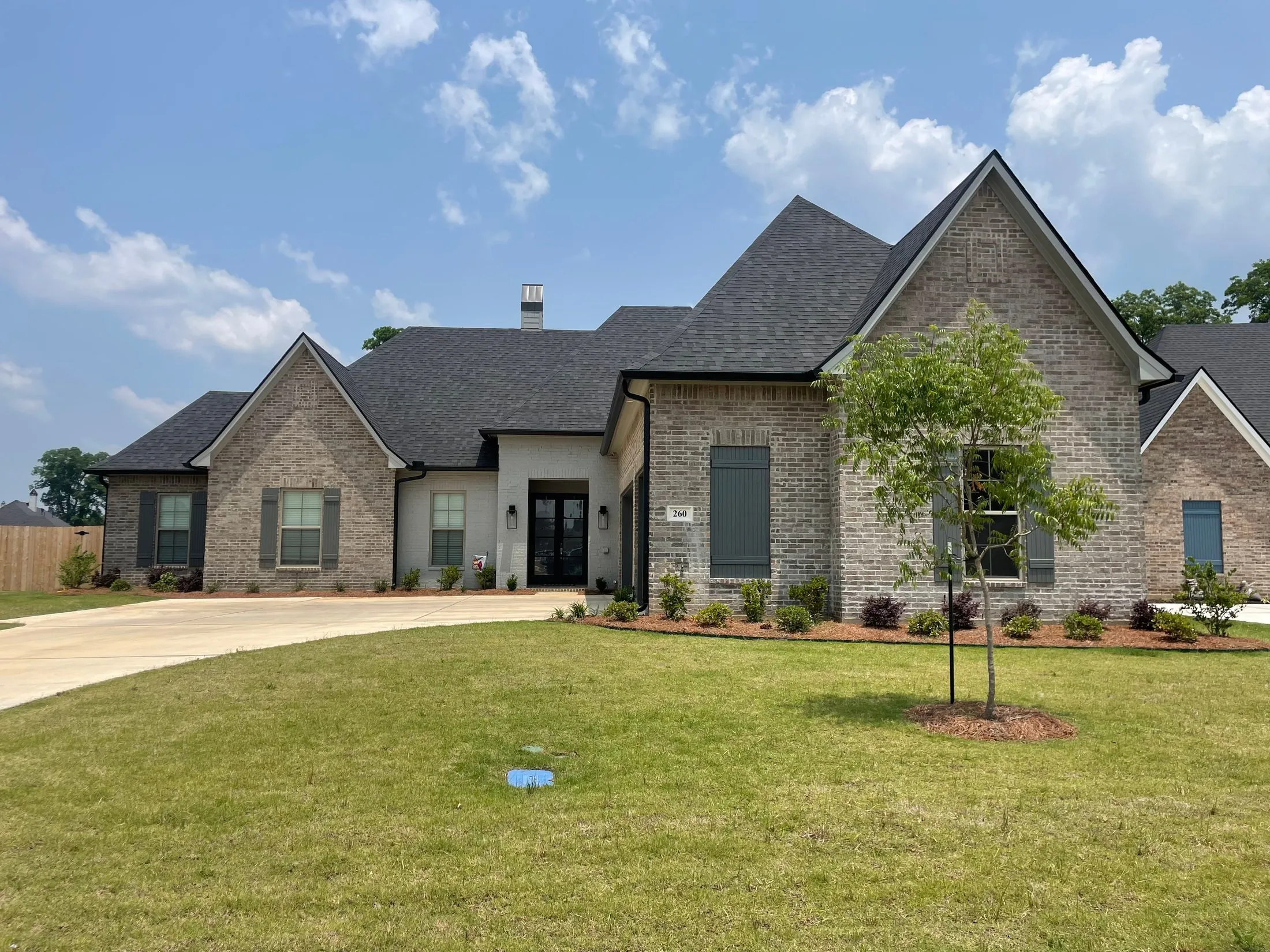 Front elevation of a large brick-and-stone home with dark gutters along the eaves