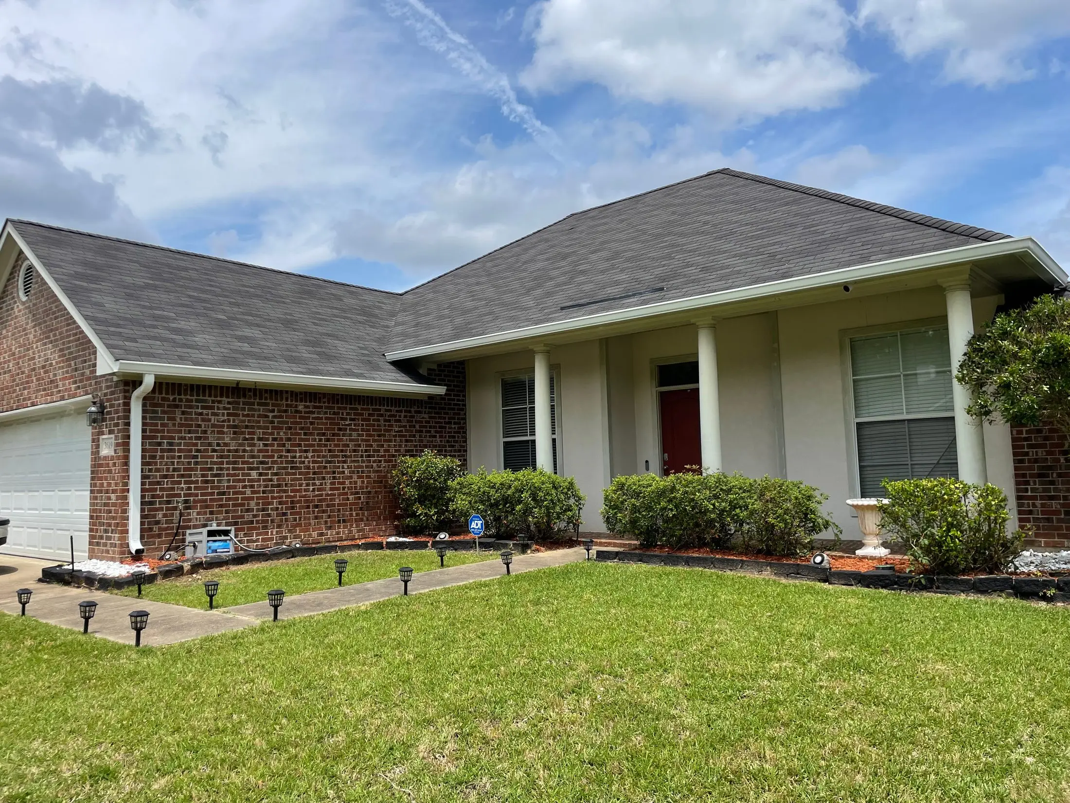Brick-and-stucco home with a hip roof and white gutters