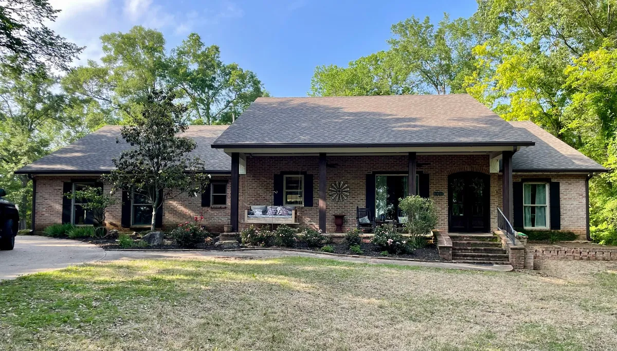 Long brick ranch home behind a deep covered porch