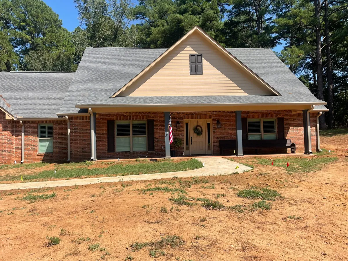 Brick-and-siding new build with a front porch, the yard still bare dirt