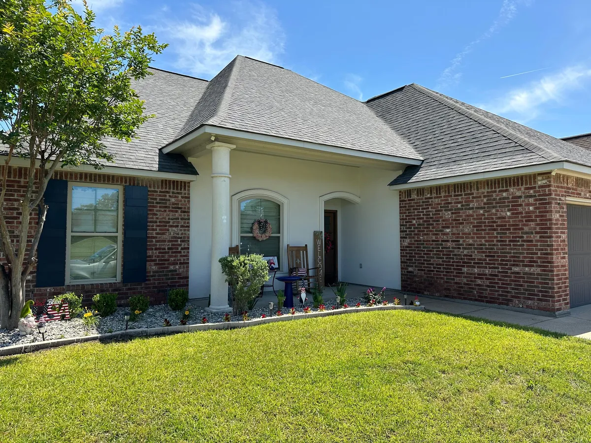 Before: Brick-and-stucco home with a front porch and white columns, the porch roofline and eave bare fascia with no gutters
