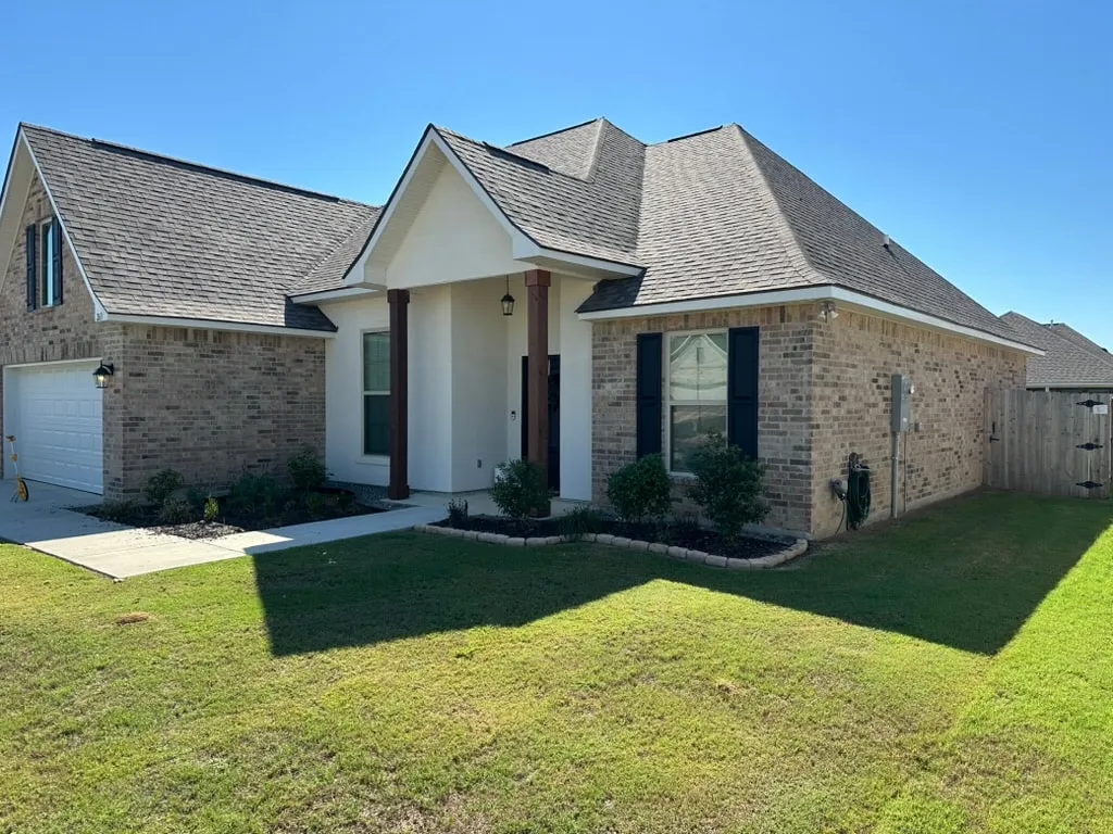 Before: Brick and stucco home in Shreveport before installation, with no gutters along the visible front and side roof edges