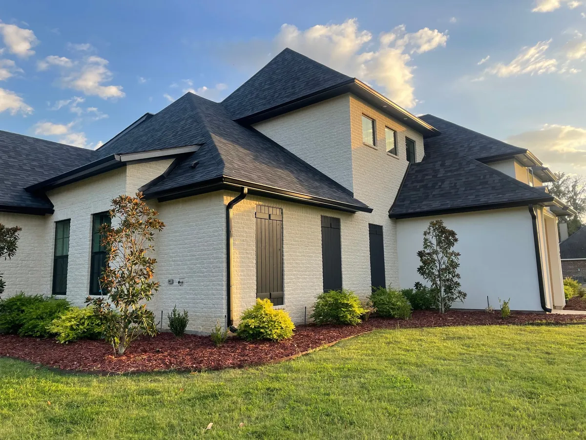 White painted-brick two-story home with black gutters and downspouts and new landscaping