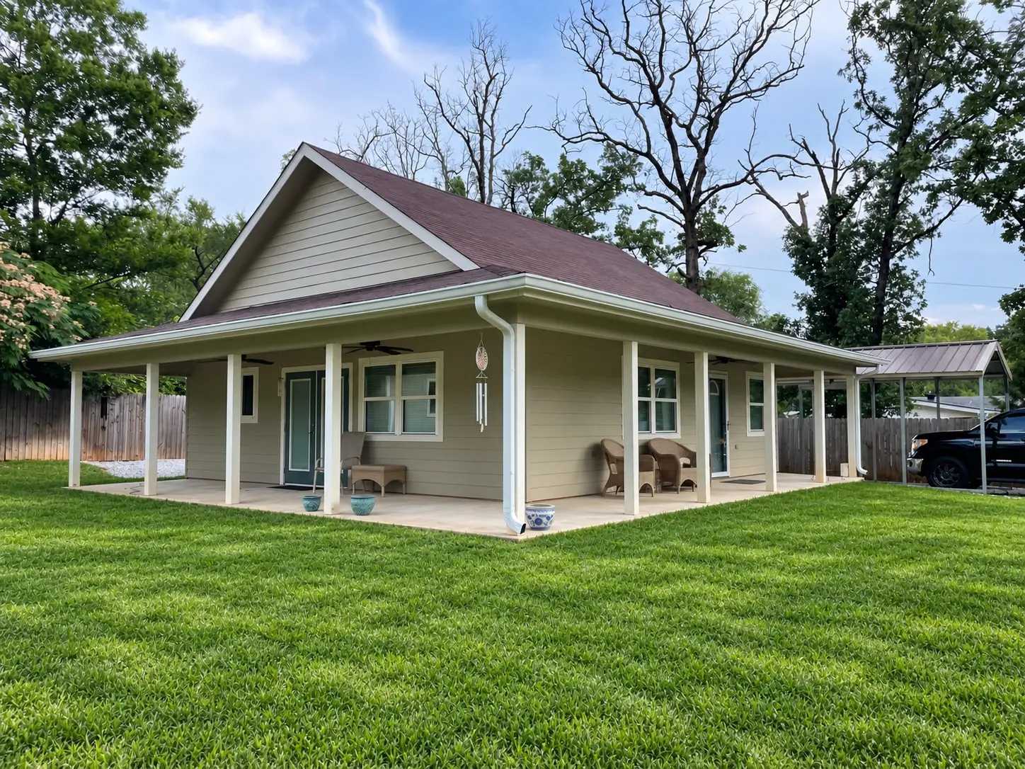 Home with a wide wraparound porch, white gutters and downspouts, and a lush green lawn